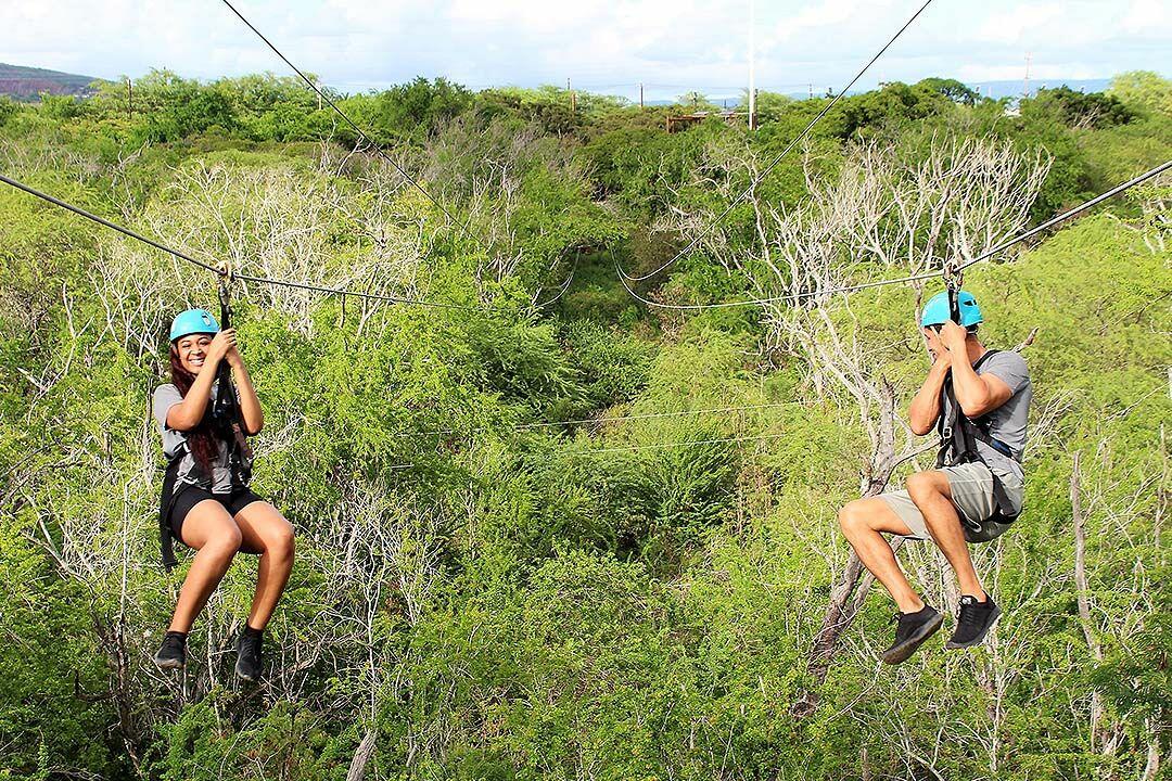 Two people ziplining side by side at Coral Crater