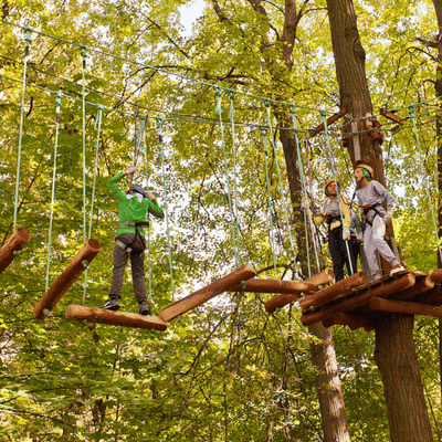Participants walk suspended wooden beams during ropes training, enhancing balance, focus, and coordination