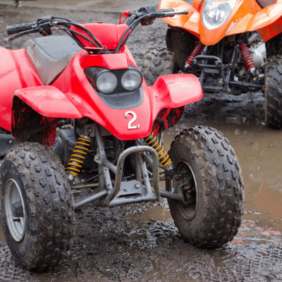Red four-wheeler parked on muddy trail, showcasing off-road fun and atv riding for kids