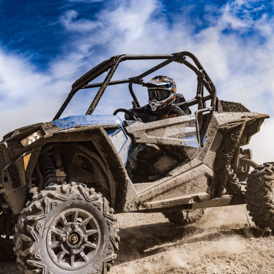 A rider speeds through dusty terrain in a rugged sport ATV built for off-road thrills
