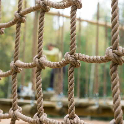 Close-up view of a thick rope net obstacle on an outdoor ropes course adventure park
