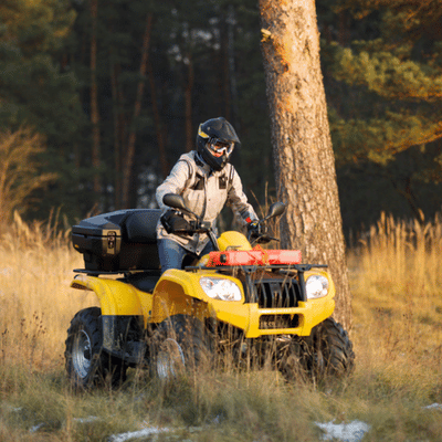A lone rider on a yellow sport ATV explores grassy terrain, geared for outdoor adventure